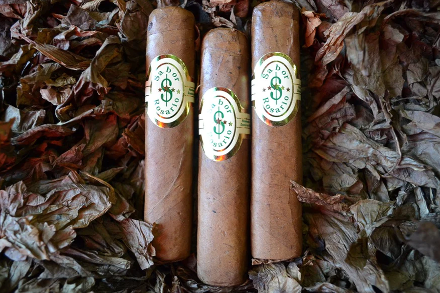 This is a image of a stack of 1 to 5 cigars. They are layed on a of  Background feild of tabaco.