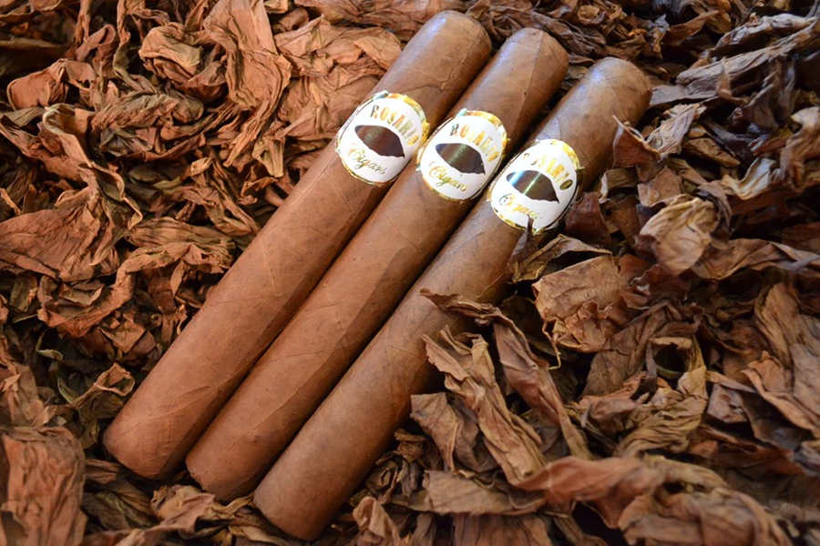 This is a image of a stack of 1 to 5 cigars. They are layed on a of Background feild of tabaco.