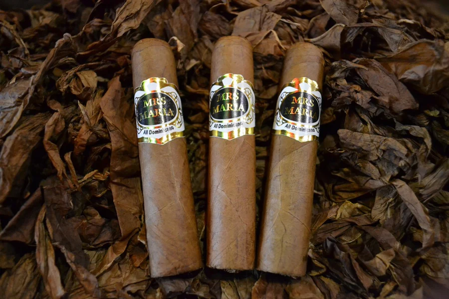 This is a image of a stack of 1 to 5 cigars. They are layed on a of Background feild of tabaco.