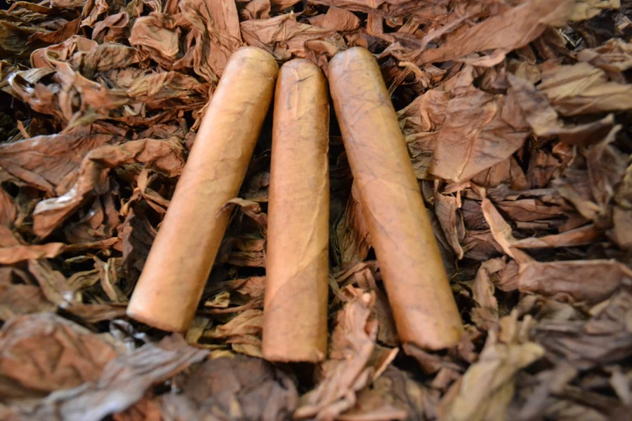This is a image of a stack of 1 to 5 cigars. They are layed on a of Background feild of tabaco.