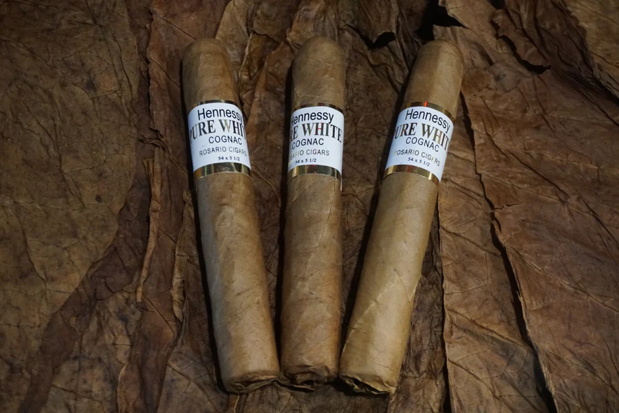 This is a image of a stack of 1 to 5 cigars. They are layed on a of  Background feild of tabaco.