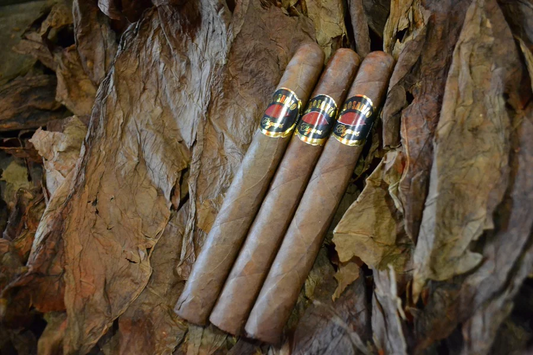 This is a image of a stack of 1 to 5 cigars. They are layed on a of  Background feild of tabaco.