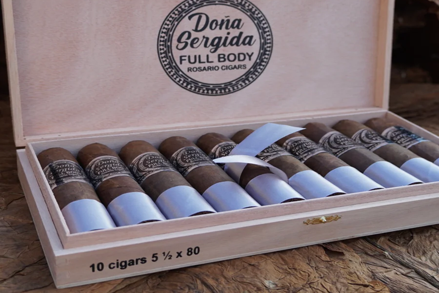 This is a image of a stack of 10 or more cigars. They are Pleaced together in a small wooden box that has a cover to it with the company's logo that is wrapped in a circular reef like design.