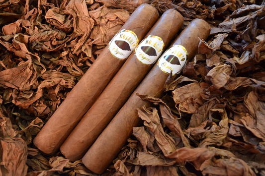This is a image of a stack of 1 to 5 cigars. They are layed on a of  Background feild of tabaco.