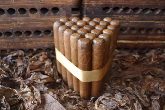This is a image of a stack of 20 to 25 cigars. They are Rapped together with a thin colored paper ranging from cool whites to firey red wrappings they are forming a trianglur shape simular to a mountain or pyramid. While the Background shows the cigars placed on a feild of tabaco.