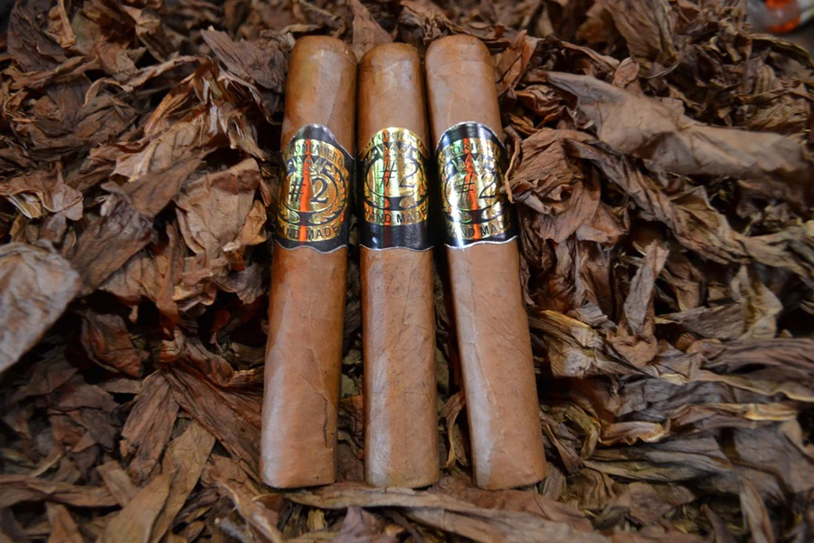 This is a image of a stack of 1 to 5 cigars. They are layed on a of  Background feild of tabaco.