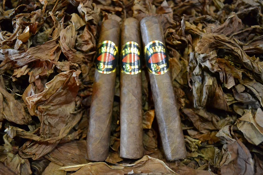 This is a image of a stack of 1 to 5 cigars. They are layed on a of  Background feild of tabaco.