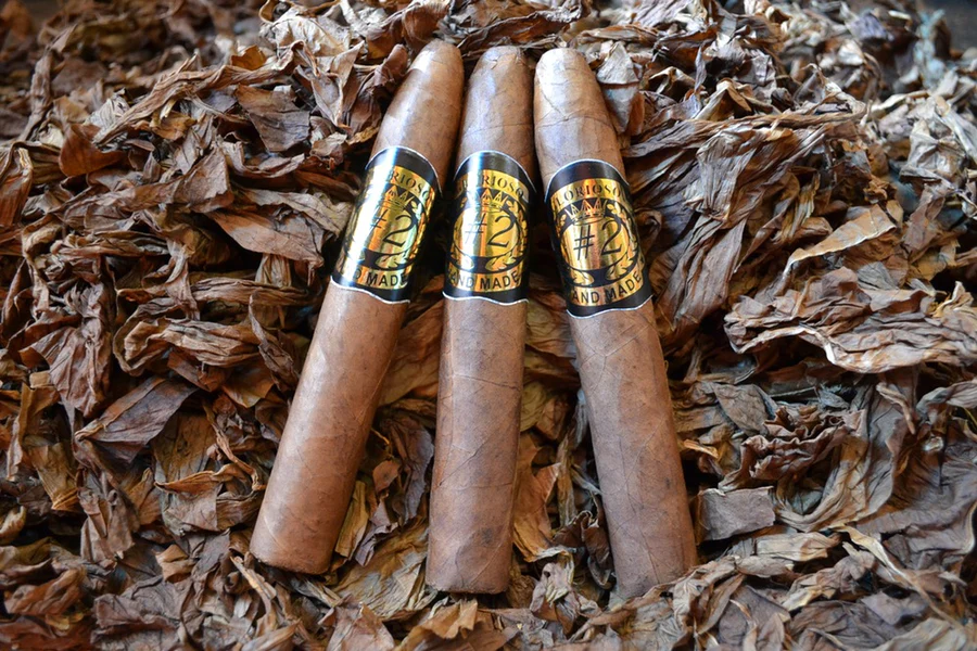 This is a image of a stack of 1 to 5 cigars. They are layed on a of  Background feild of tabaco.