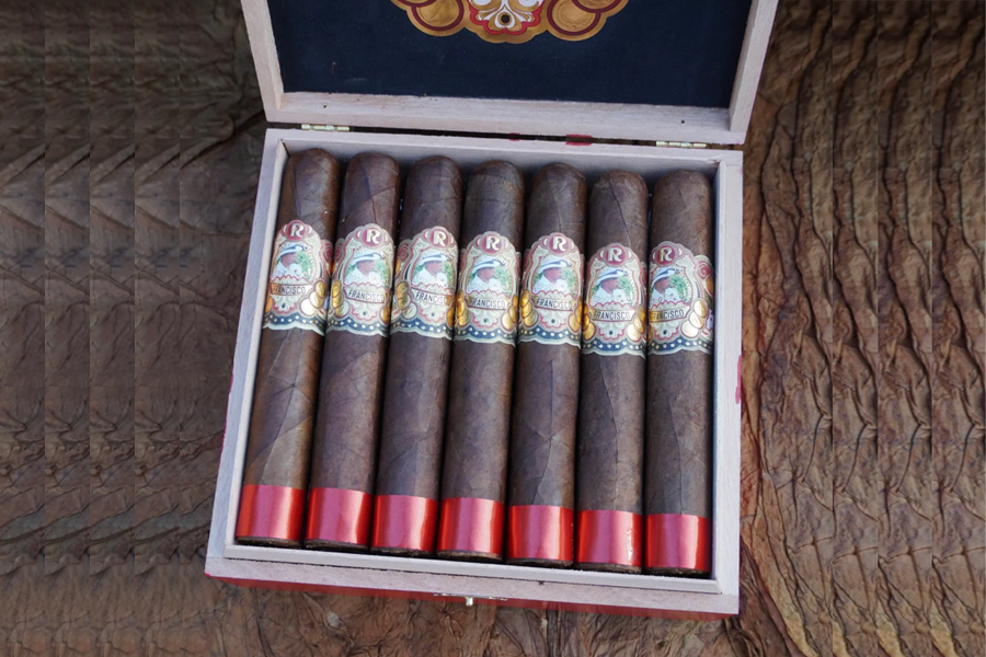 This is a image of a stack of 7 or more cigars. They are Pleaced together in a small wooden box that has a cover to it with the company's logo.