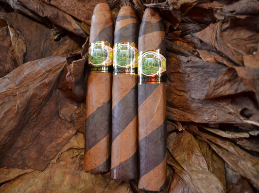 This is a image of a stack of 1 to 5 cigars. They are layed on a of  Background feild of tabaco. These cigars have a vertical two toned design resembling a candy cane of light and dark browns.