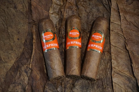 This is a image of a stack of 1 to 5 cigars. They are layed on a of  Background feild of tabaco. These cigars are stubby in size.